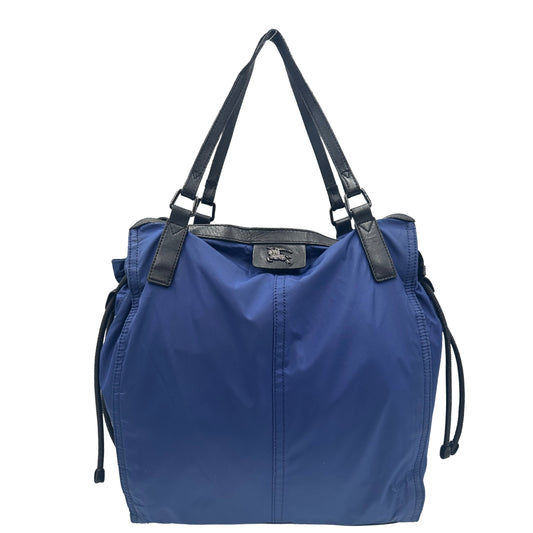 Shopper Burberry in nylon blu con finiture in pelle nera, da indossare a spalla. Rifinita con lacci laterali e parti metalliche argentate. Originale, usato, in buone condizioni, con lievi segni di utilizzo sul tessuto.