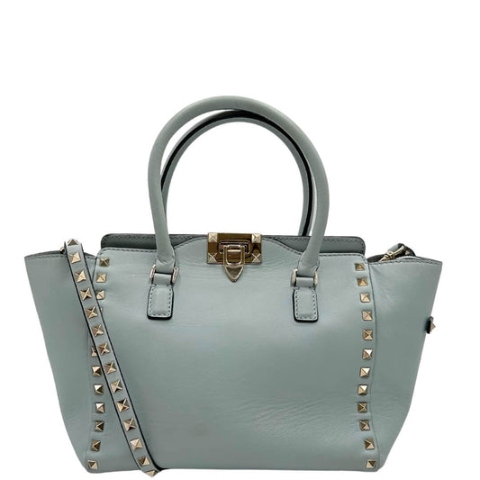 Borsa Valentino Garavani in pelle color azzurro baby e parti metalliche oro chiaro; munita di doppi manici e una tracolla amovibile impreziosita da borchie piramidali. Completa di dustbag e borchie sostitutive.