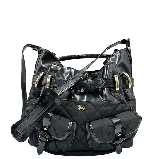 Shopper Burberry in tessuto trapuntato nero con finiture in pelle lucida tono su tono, arricchita da una fibbia decorativa. Munita di un manico singolo e una tracolla regolabile. Parti metalliche dorate. Originale, usato, condizioni ottime.