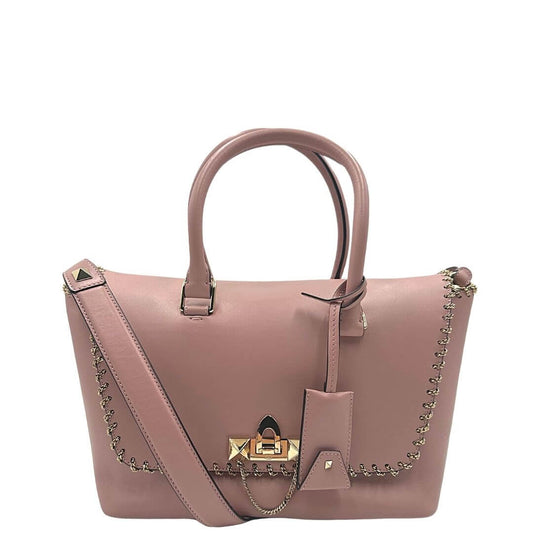 Front di una borsa Valentino Garavani in pelle rosa antico, rifinita con microcatene e parti metalliche in oro chiaro. Indossabile a mano o a tracolla. Completa di dustbag e cartellini.