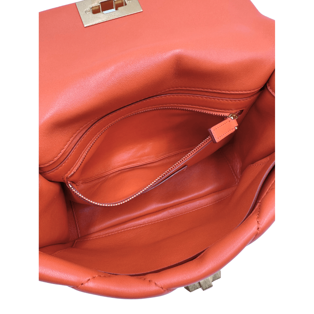 Tasca Borsa Valentino Garavani in Pelle trapuntata arancione, impreziosita da borchie piramidali dorate, munita di tracolla in catena scorrevole. Indossabile a tracolla, a mano e a spalla