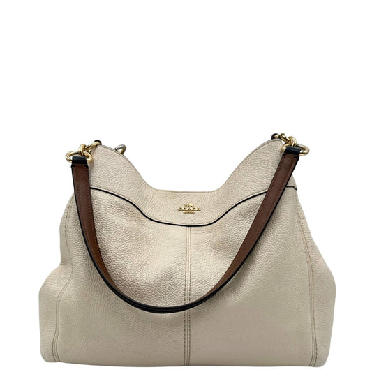 front Borsa Coach in pelle martellata color bianco avorio con parti metalliche dorate; munita di doppi manici in pelle nera e marrone, da indossare a spalla.