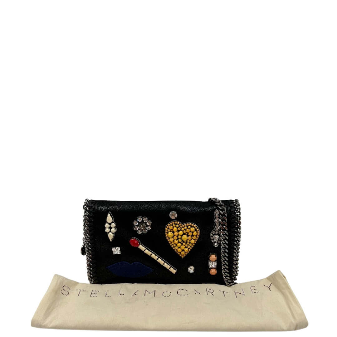 Borsa Stella McCartney in tessuto vegano nero impreziosita da patch decorativi con strass e pietre colorate. Rifinita con parti metalliche argentate e munita di una tracolla in catena. Completa di dustbag. Originale, usato, in condizioni eccellenti.
