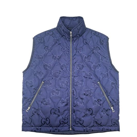 Smanicato Gucci in 100% Poliammide blu navy con iconica trama GG Jumbo. Chiusura con cerniera, doppie tasche laterali e una sul retro con chiusura a strappo. Rifinito con parti metalliche argentate. Originale, usato, condizioni eccellenti.