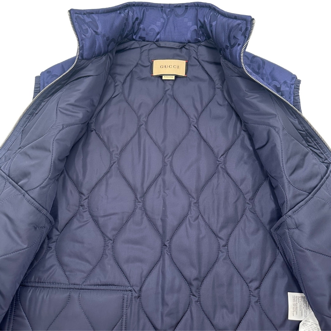 Interno Smanicato Gucci in 100% Poliammide blu navy con iconica trama GG Jumbo. Chiusura con cerniera, doppie tasche laterali e una sul retro con chiusura a strappo. Rifinito con parti metalliche argentate. Originale, usato, condizioni eccellenti.