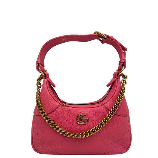 Borsa Gucci Aphrodite Small in pelle martellata rosa, impreziosita dalle doppie G in metallo dorato. È dotata di un manico in catena, un secondo manico in pelle con fibbia regolabile, e una prolunga aggiuntiva che consente di indossarla comodamente anche a tracolla. Completa di dustbag. Originale, usato, condizioni eccellenti.