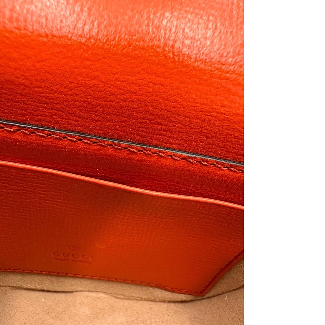Tracolla Gucci in pelle arancione e inserti metallici dorati; munita di un manico in catena e una tracolla in tessuto web blu e rosso e finiture in pelle tono su tono, interno