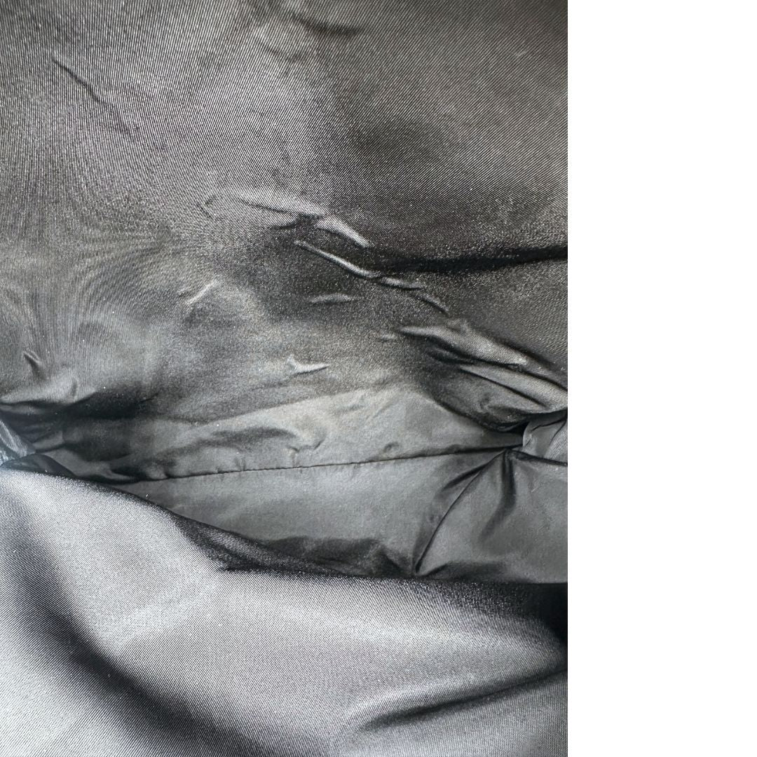 Interno di uno zaino Prada in nylon nero e finiture in tessuto. Dettagli metallici argentati e munito di svariate tasche.