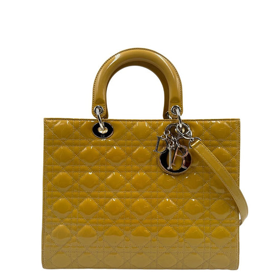 Borsa Lady Dior in pelle verniciata giallo mostarda con doppi manici rigidi e una tracolla regolabile e amovibile. Rifinita con parti metalliche argentate. Completa di scatola e card d'autenticità. Originale, usato, condizioni ottime.