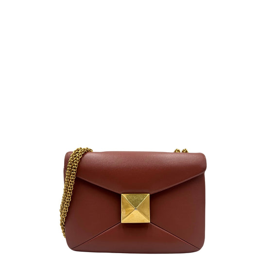 Borsa One Stud Valentino Garavani in pelle color marsala con tracolla in catena scorrevole e iconica chiusura con maxi borchia piramidale. Completa di corredo. Originale, usato, in condizioni ottime.