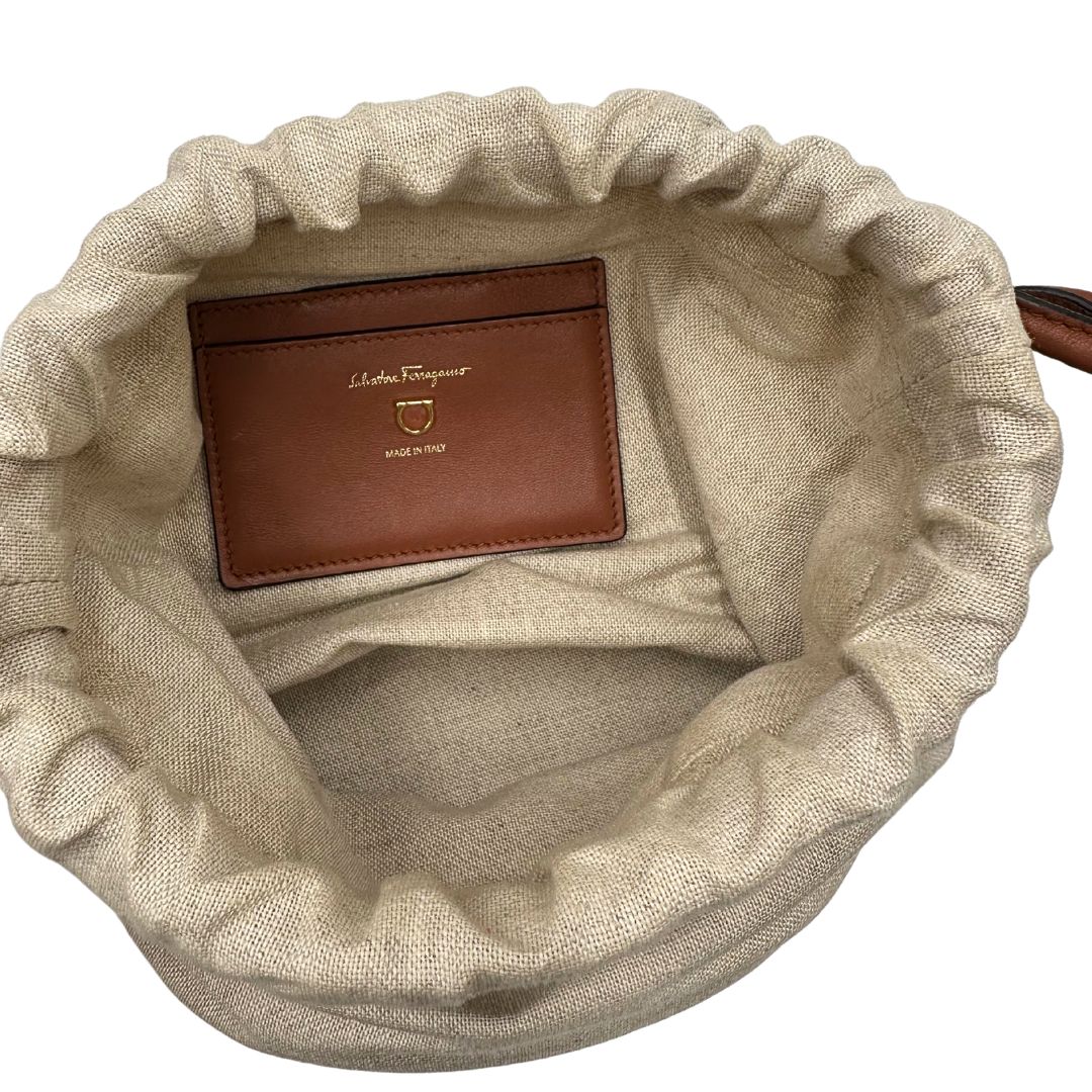 Interno Borsa a secchiello Salvatore Ferragamo in pelle marrone cognac con sacca interna in tela beige con chiusura a coulisse. Munita di un manico stondato e tracolla, parti metalliche dorate. Completa di dustbag. Originale, usato, in condizioni ottime.