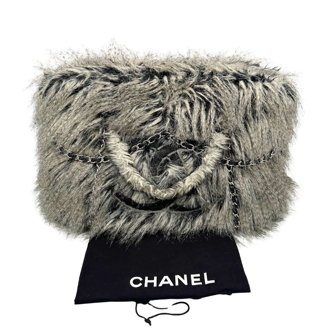 Borsa Chanel Grey Arctic in pelliccia sintetica sui toni del grigio e nero sfumato con parti metalliche argentate. Impreziosita da catene con pelle intrecciata e rifinita con logo CC sul front. Munita di doppi manici in catena e pelliccia. Completa di dustbag. Originale, usato, in condizioni ottime.