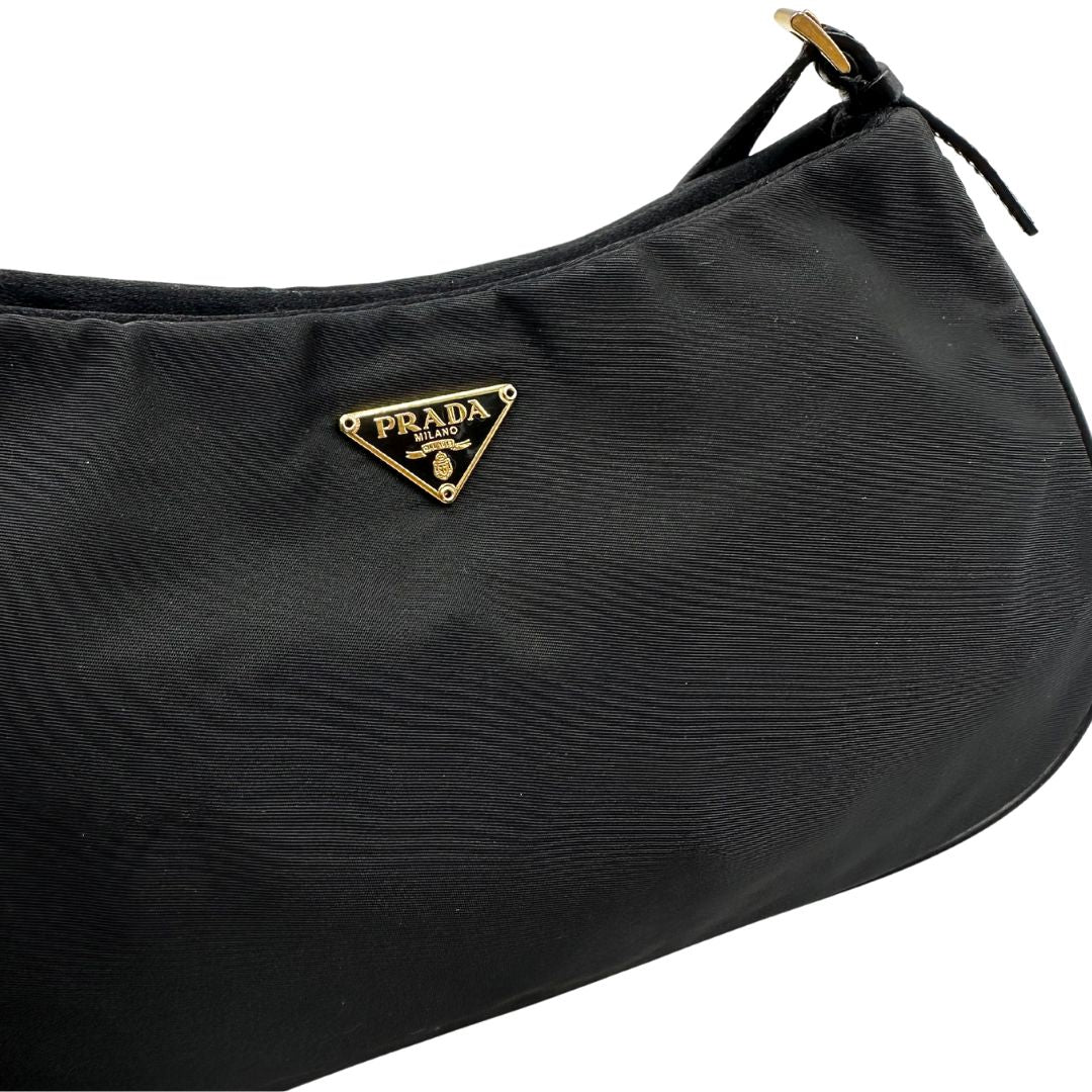 Borsa Prada in nylon nero con parti metalliche dorate e finiture in pelle tono su tono. Munta di un manico in catena leggermente regolabile con fibbie, e rifinita con classico logo triangolare sul front. Completa di dustbag. Originale, usato, in condizioni ottime.