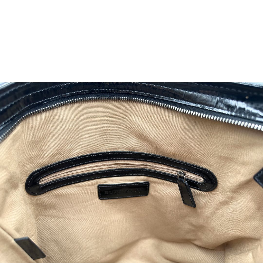 Interno di una borsa tote Burberry in canvas trama tartan, finiture in pelle lucida nere e parti metalliche effetto renio.