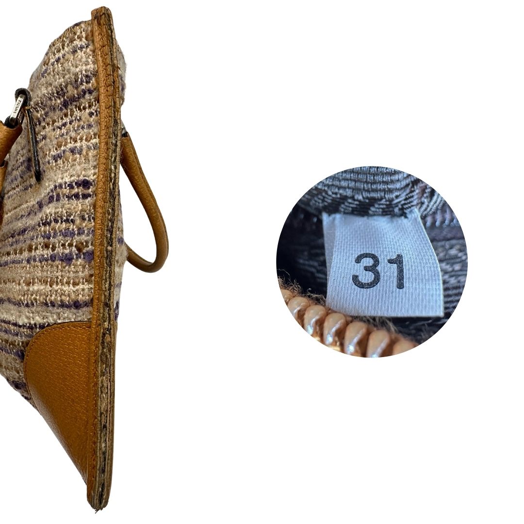 Laterale e codice di una borsa Tote Prada mini in tweed nelle tonalità dei beige e viola, finiture in pelle cammello con parti metalliche argentate. Munita di doppi manici stondati, indossabile a mano. Completa di dustbag.