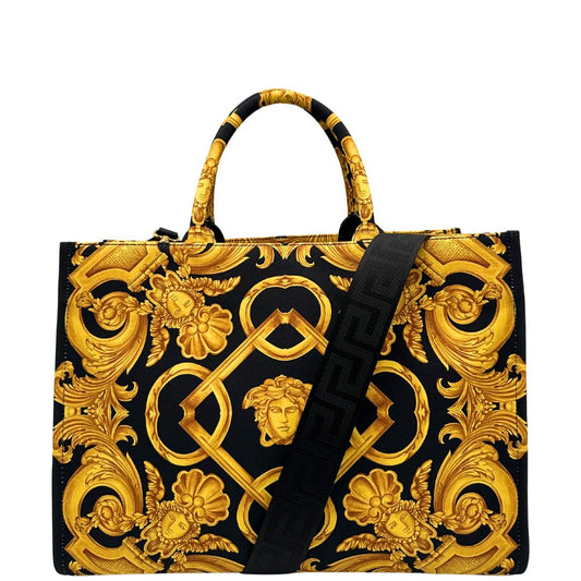 Front di una borsa Versace in tela com motivo jacquard barocco in nero e giallo tipico della Maison. Presenta doppi manici stondati e una tracolla amovibile in tessuto motivo greca, con dettagli in pelle neri. Completa di dustbag.