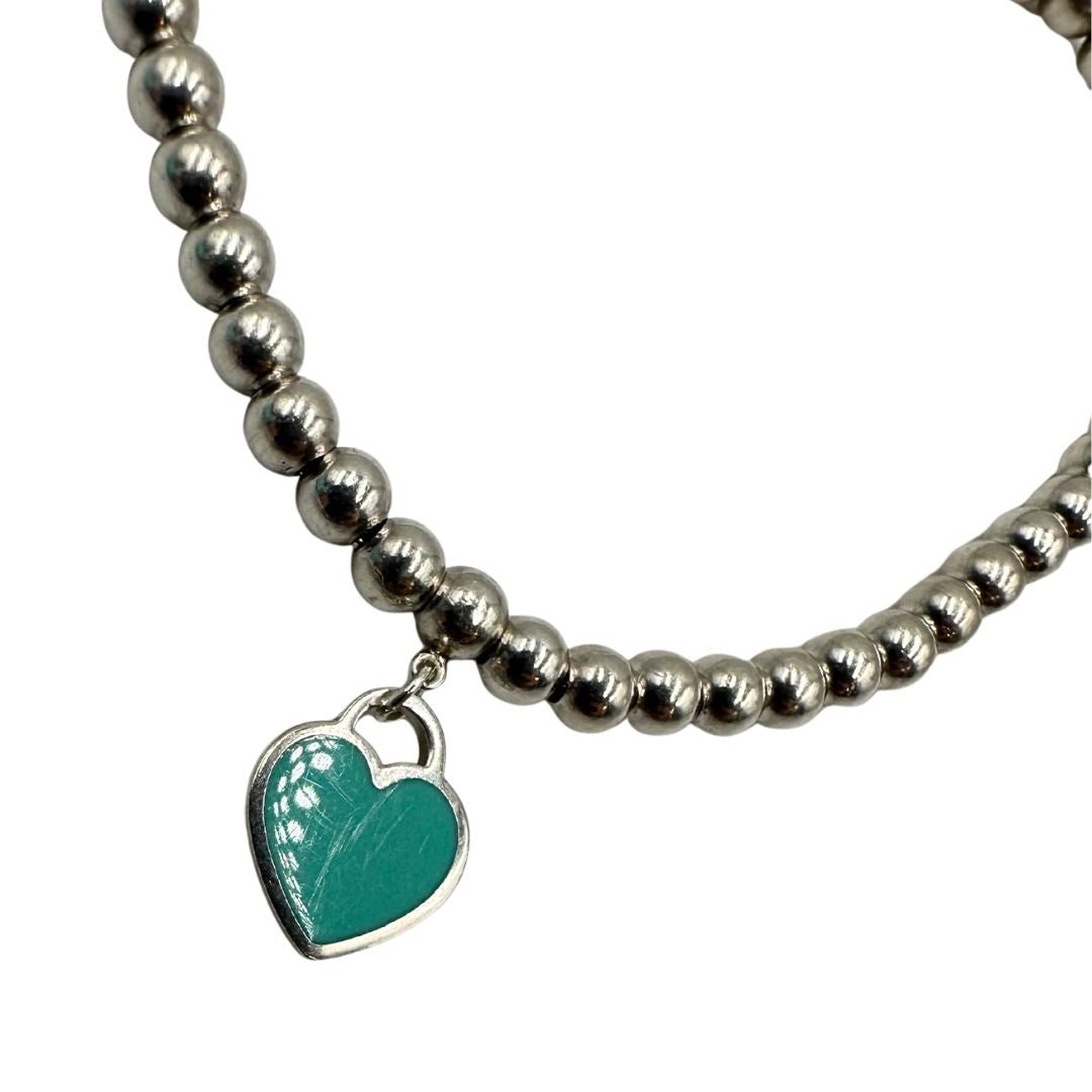Bracciale Tiffany&Co. della collezione Return to Tiffany in argento 925 composto da sfere circolari e ciondolo cuore smaltato in verde Tiffany. Completo di scatola e sacchetto anti polvere.