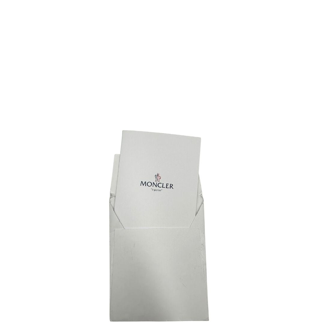 Cartellino di una borsa Moncler in poliuretano color caramello effetto imbottito e finiture in pelle tono su tono, con metalleria dorata. Da indossare a spalla.