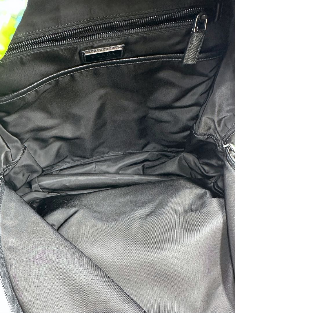 Interno di uno zaino Prada Radar in nylon tecnico con chiusura a zip. Design caratterizzato da stampa grafica multicolor effetto radar. Struttura con ampio scomparto principale, tasca frontale a zip e tasca interna con zip. Spallacci regolabili con imbottitura e pannello posteriore traspirante in mesh per un maggiore comfort. Manico superiore in pelle nera saffiano. Dettagli con logo triangolo Prada smaltato applicato sul fronte.
