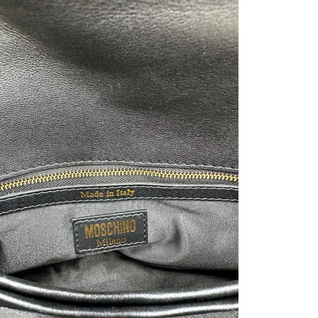 Interno di una Borsa Moschino in pelle nera con inserti metallici dorati, arricchita da borchie dorate, zip frontale con maxi tirazip e applicazioni geometriche. munita di una tracolla regolabile non amovibile. Completa di Card d'autenticità Misure. Originale, Usata, di lusso, in ottime condizioni.