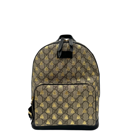 Front di un Zaino Gucci in canvas GG beige con finiture in pelle nere e parti metalliche dorate; presenta una stampa di api dorate su tutta la superficie, munito di un manico e bretelle in tessuto regolabili. Originale, usato, di lusso, in ottime condizioni.