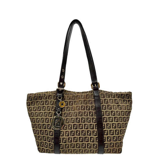 Front di una borsa Fendi in tessuto beige trama FF marrone, con finiture in pelle testa di moro. Dotata di doppi manici leggermente regolabili e parti metalliche dorate. Indossabile a spalla.