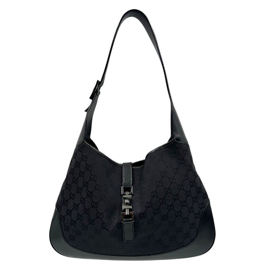 Front di una borsa Gucci in tessuto nero GG con finiture in pelle tono su tono e parti metalliche argentate. Munita di un manico leggermente regolabile.