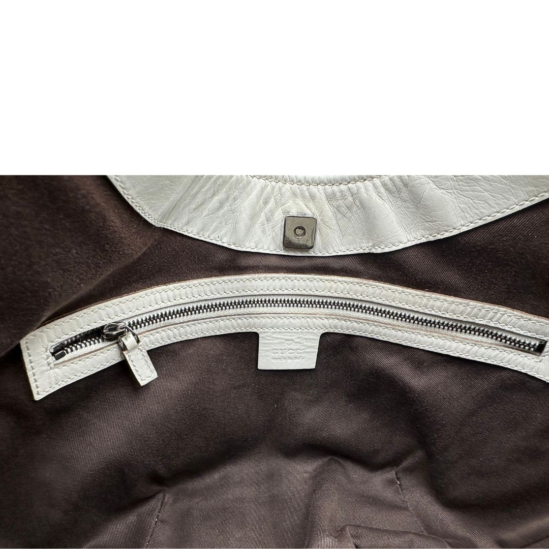 Interno di una borsa Gucci in tessuto avorio GG con parti in pelle bianco gesso e parti metalliche argentate. Indossabile a spalla.