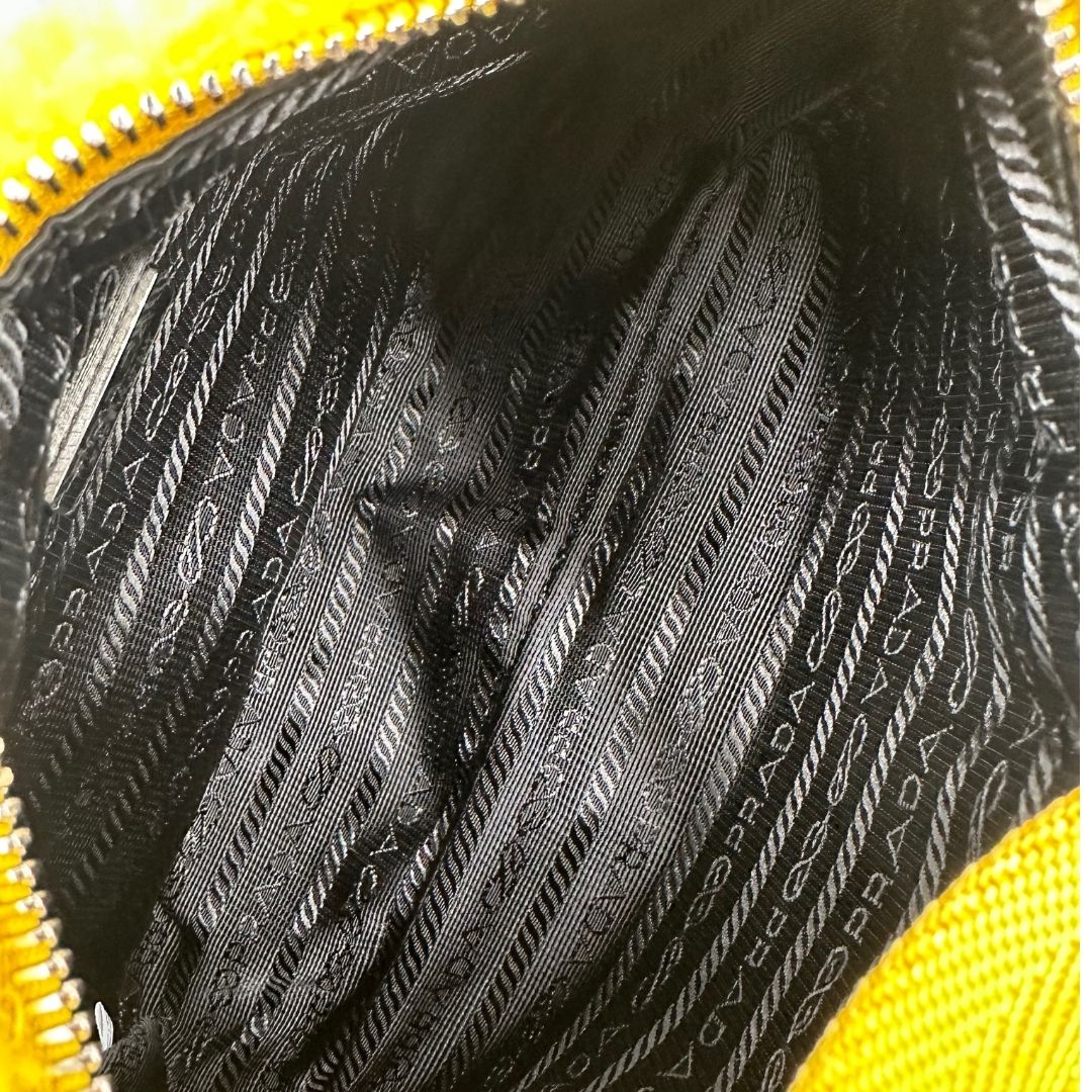 interno Borsa Prada in spugna gialla con logo nero sul front e parti metalliche argentate; munita di un manico singolo in tessuto, indossabile a spalla o a mano. Completa di dustbag, di lusso, originale, ottime condizioni.