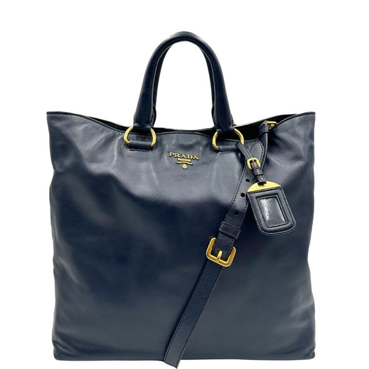 Front di una Borsa Prada in pelle blu notte con parti metalliche dorate; munita di un accessorio porta address, doppi manici stondati e una tracolla amovibile e regolabile. Indossabile a mano oppure a tracolla. Originale, usata, di lusso, in ottime condizioni.