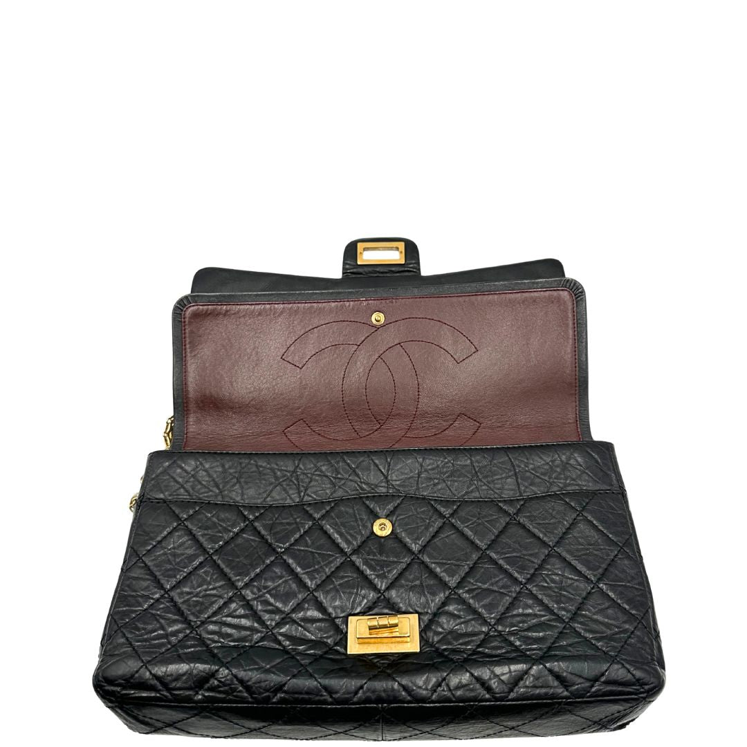 Apertura di una borsa Chanel 2.55 in pelle aged nera trapuntata, con parti metalliche dorate. Munita di una tracolla scorrevole in catena. Indossabile a spalla o a tracolla. Completa di scatola.