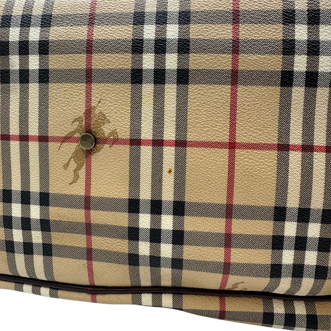 Alone sul canvas di un borsone Burberry in canvas trama tartan con finiture in pelle marrone testa di moro e parti metalliche dorate; munito di doppi manici stondati e una tracolla amovibile e regolabile.