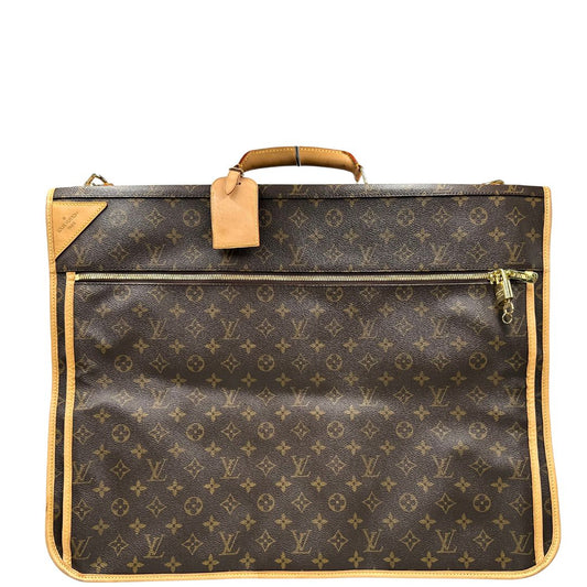 Front di una Borsa da viaggio porta abiti in canvas marrone monogram con finiture in vacchetta naturale e parti metalliche dorate; munita di un manico singolo, una tracolla amovibile e regolabile e 2 grucce. Completa di Lucchetti e una chiave, dustbag.