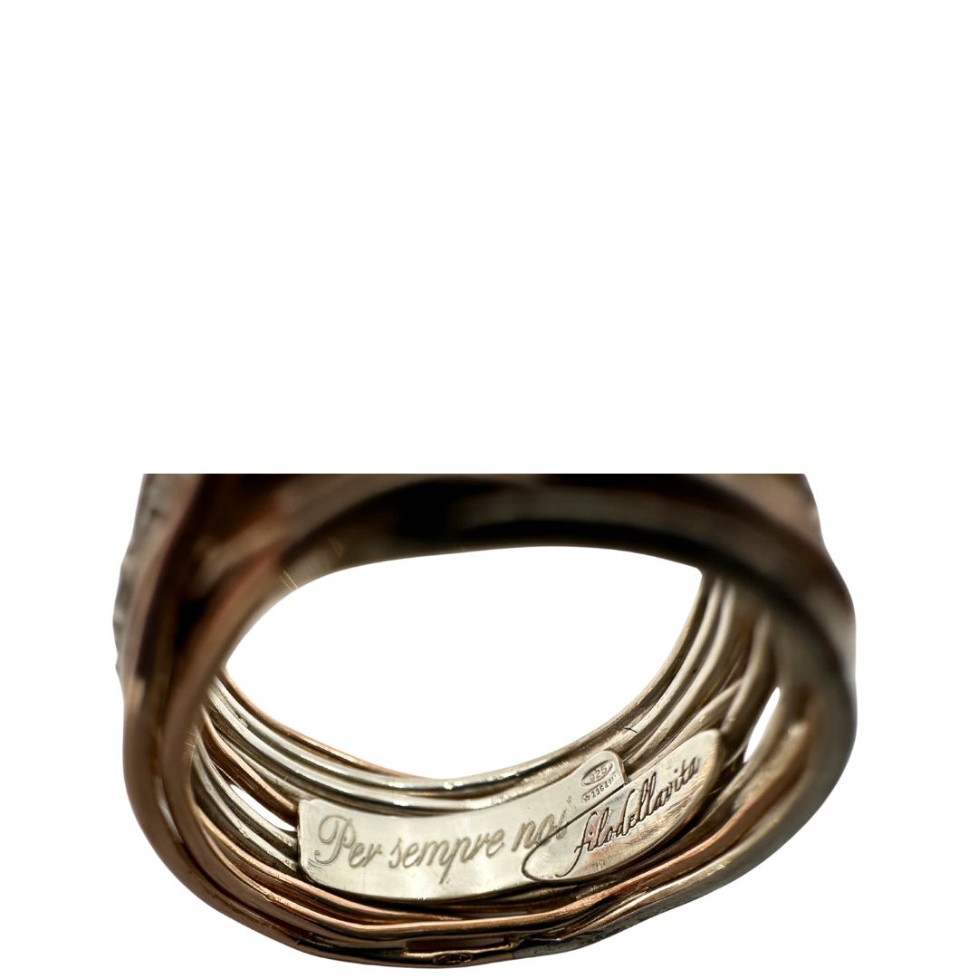 Tredici fili in oro rosa 9kt e argento 925 arricchito al palladio intrecciati, sulla cui superficie risplendono sedici diamanti bianchi taglio brillante da 0.21 ct. Completo di scatola, di lusso, originale, ottime condizioni, usato.