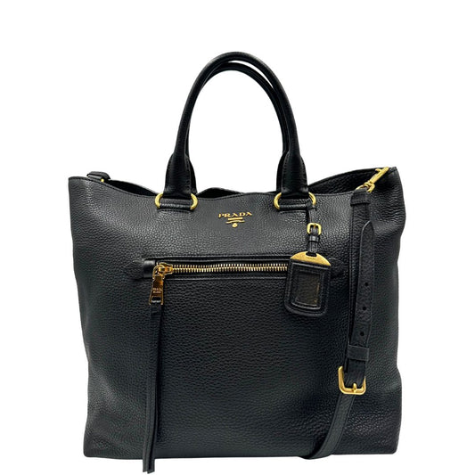 Front di una Borsa Tote Prada in pelle martellata nera con parti metalliche dorate e logo lettering sul front,; munita di doppi manici e una tracolla amovibile e regolabile. Indossabile a mano oppure a tracolla. Originale, usata, di lusso, in ottime condizioni.