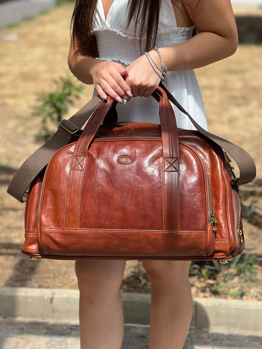 Borsone The Bridge in cuoio con parti metalliche dorate, munito di doppi manici e una tracolla in tessuto amovibile con moschettoni. Completo di cartellino.