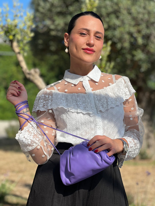 Ragazza che indossa una Clutch Bottega Veneta in pelle viola con parti metalliche argentate. Da indossare a tracolla.