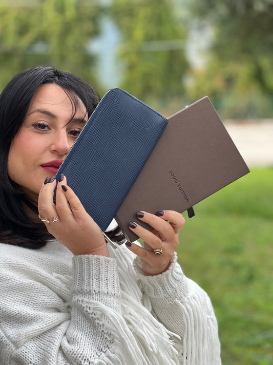 Ragazza che mostra un portafoglio Louis Vuitton in pelle Epi blu marino con parti metalliche argentate. Completo di corredo.