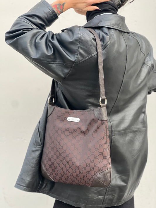 Ragazza che indossa una borsa Gucci in tessuto marrone GG con finiture in pelle tono su tono e parti metalliche argentate; munita di un manico singolo, indossabile a spalla.