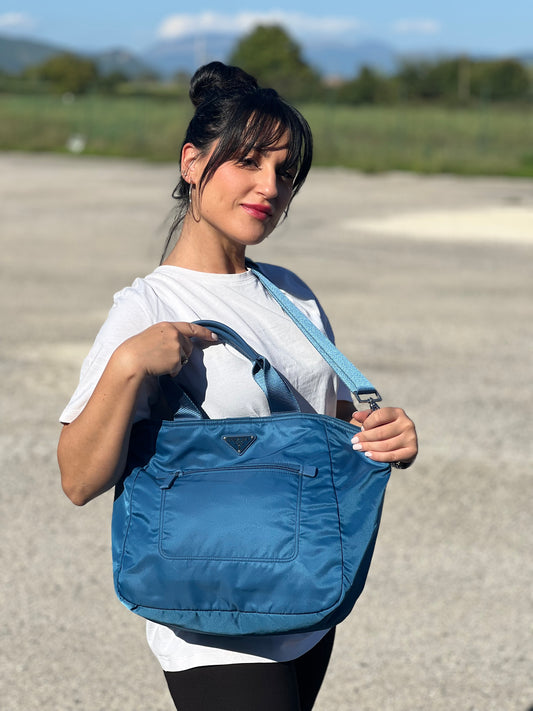 Foto indossata Borsa Prada in nylon blu oltremare con dettagli in pelle Saffiano tono su tono con parti metalliche argentate. Dotata di doppi manici e tracolla regolabile, amovibile in tessuto. Completa di dustbag e card d'autenticità. Originale, usato, in condizioni ottime.