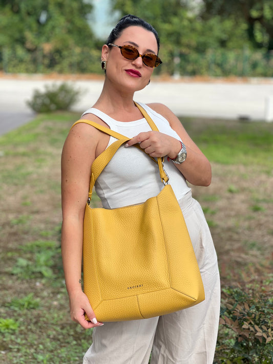 Foto indossata Secchiello Orciani in pelle martellata gialla con parti metalliche argentate. Munita di un manico singolo e tracolla regolabile, e amovibile. Rifinita con logo lettering sul front. Completo di dustbag. Originale, usato, in condizioni ottime.