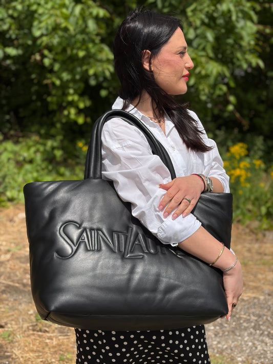 Ragazza che indossa una borsa Saint Laurent in pelle imbottita nera con logo in rilievo Saint Laurent sul front, usata, originale, second hand, in condizioni eccellenti.