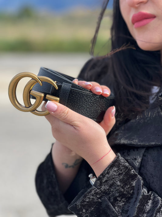 Ragazza che mostra una cintura Gucci in pelle martellata nera, con parti metalliche dorate. Completa di dustbag.