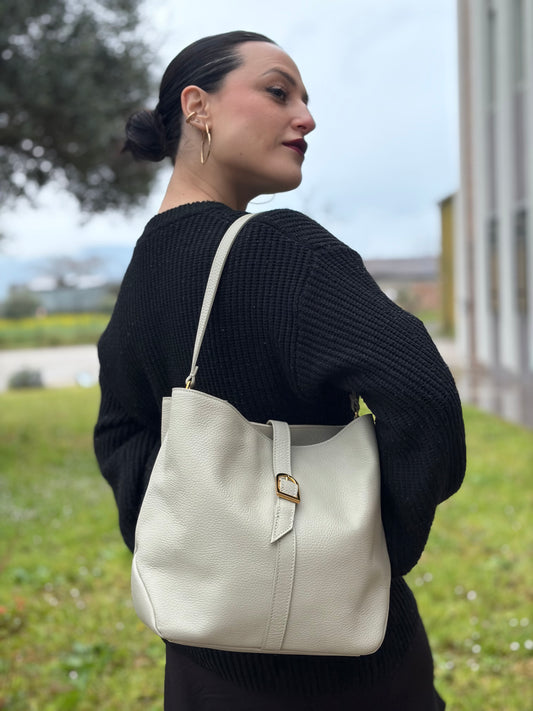 Ragazza che indossa una borsa Coccinelle in morbida pelle color ghiaccio, indossabile a spalla, usata, originale, second hand, in ottime condizioni.