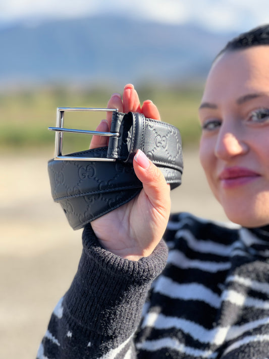 Ragazza che mostra una cintura Gucci in pelle nera GG con parti metalliche argentate.