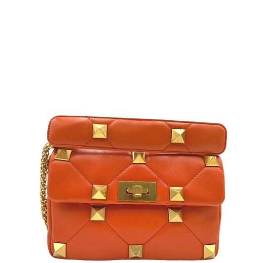 Front Borsa Valentino Garavani in Pelle trapuntata arancione, impreziosita da borchie piramidali dorate, munita di tracolla in catena scorrevole. Indossabile a tracolla, a mano e a spalla