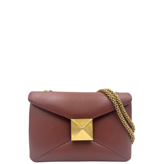 Front di una borsa One Stud Valentino Garavani in pelle color marsala con tracolla in catena scorrevole e iconica chiusura con maxi borchia piramidale. Completa di dustbag.