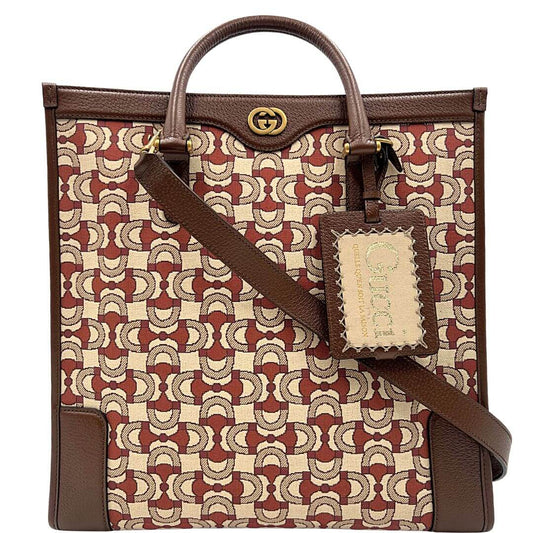 Tote Gucci in tessuto Jacquard beige, con stampa morsetto Horsebit sui toni del rosso porpora e beige. Impreziosita da finiture in pelle marrone e parti metalliche dorate. Munita di doppi manici stondati e tracolla regolabile, e rimovibile. Completa di busta logata. Originale, usato, in condizioni eccellenti.