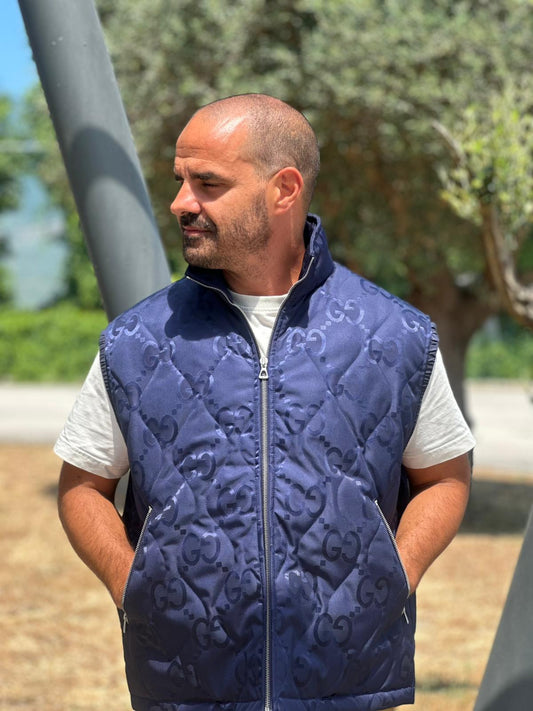 Smanicato Gucci in 100% Poliammide blu navy con iconica trama GG Jumbo. Chiusura con cerniera, doppie tasche laterali e una sul retro con chiusura a strappo. Rifinito con parti metalliche argentate. Originale, usato, condizioni eccellenti.