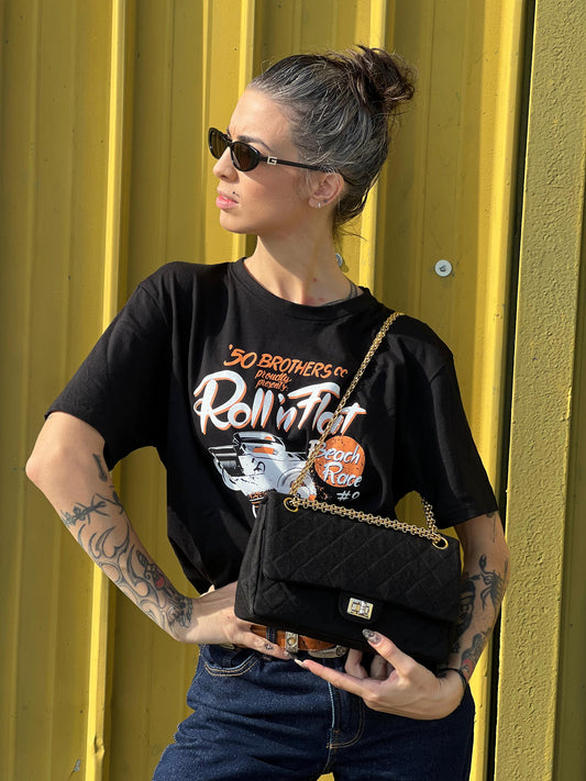 Ragazza che indossa una borsa Chanel 2.55 in tessuto nero trapuntato con parti metalliche dorate. Munita di una tracolla scorrevole in catena. Completa di corredo. Originale, usato, in condizioni ottime.